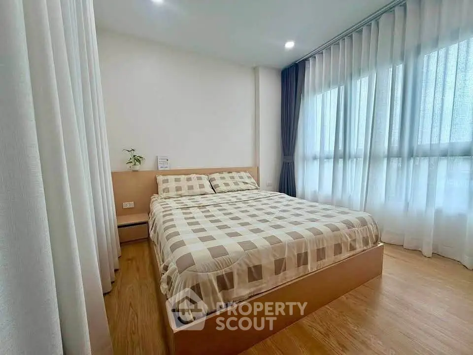Cozy bedroom with large windows and modern decor, perfect for relaxation.