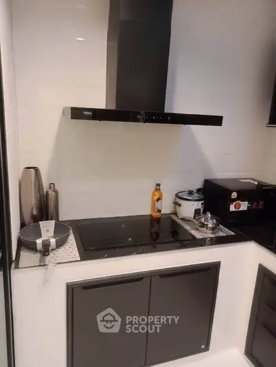 Modern kitchen with sleek black cabinetry and appliances, featuring a stylish range hood.