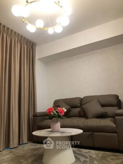 Elegant living room with modern sofa, chic chandelier, and stylish coffee table in cozy apartment.