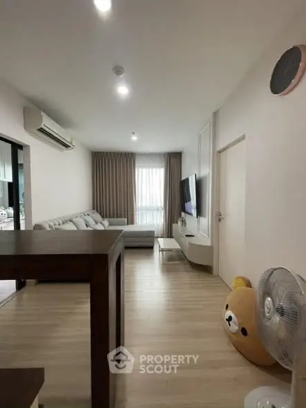 Modern living room with cozy sofa and wall-mounted TV, featuring stylish decor and ample natural light.