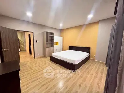 Spacious modern bedroom with wooden flooring and stylish furniture