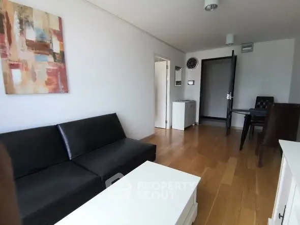 Modern living room with sleek black sofa and wooden flooring