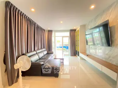Spacious modern living room with large TV and leather sofa, perfect for relaxation.