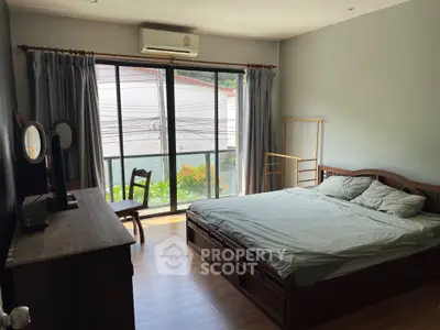 Cozy bedroom with large window and wooden furniture, perfect for relaxation and comfort.