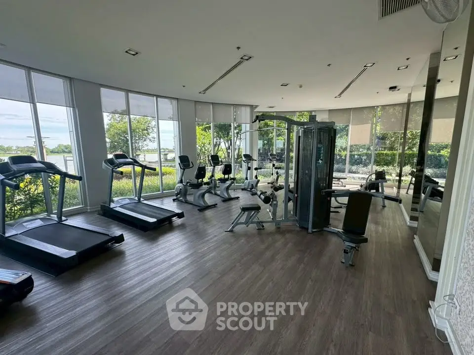 Spacious modern gym with large windows and state-of-the-art equipment in a luxury residential complex.