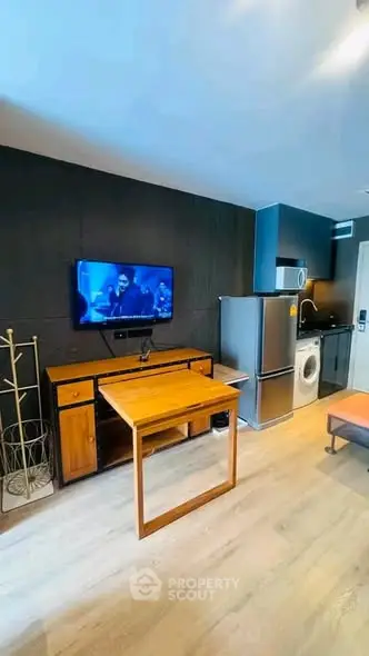 Modern apartment interior with sleek kitchen and cozy living area featuring a wall-mounted TV and stylish furniture.