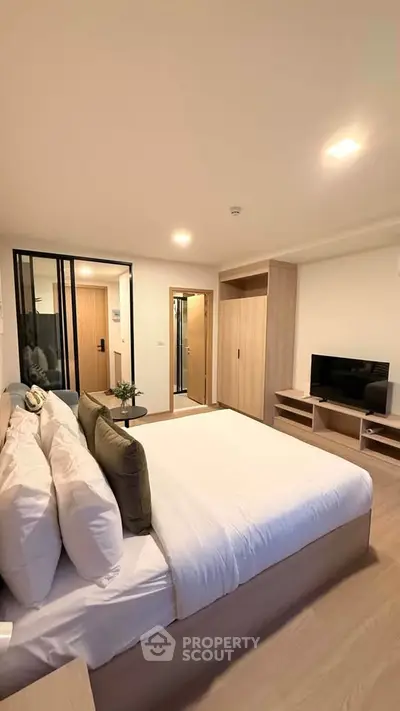 Modern bedroom with cozy bed, TV, and stylish decor in a contemporary apartment.