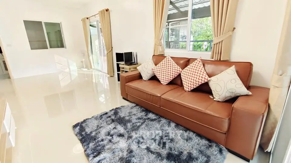 Spacious living room with modern leather sofa and plush rug, ideal for relaxation.