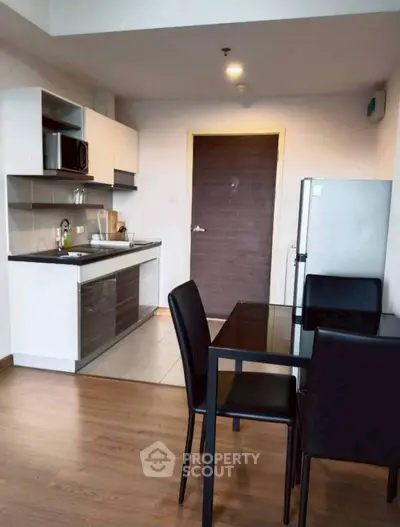 Modern kitchen with dining area, featuring sleek cabinetry and stainless steel appliances.