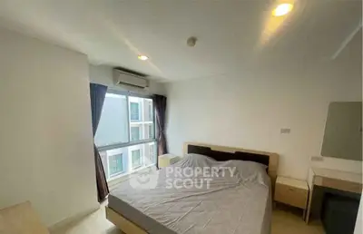Modern bedroom with large window and natural light in a stylish apartment.