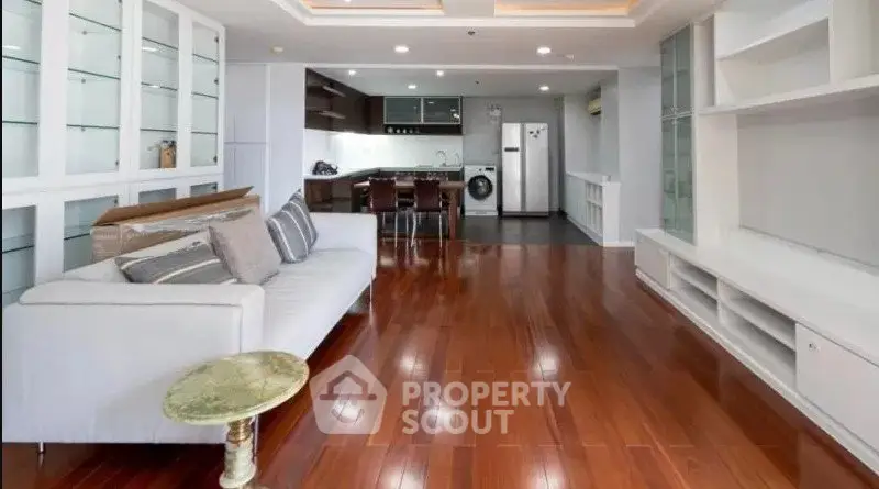 Spacious living room with open kitchen and elegant wooden flooring.