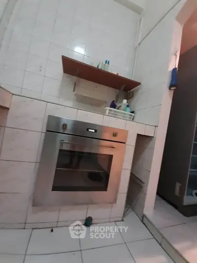 Compact kitchen with built-in oven and tiled walls, ideal for efficient cooking space.