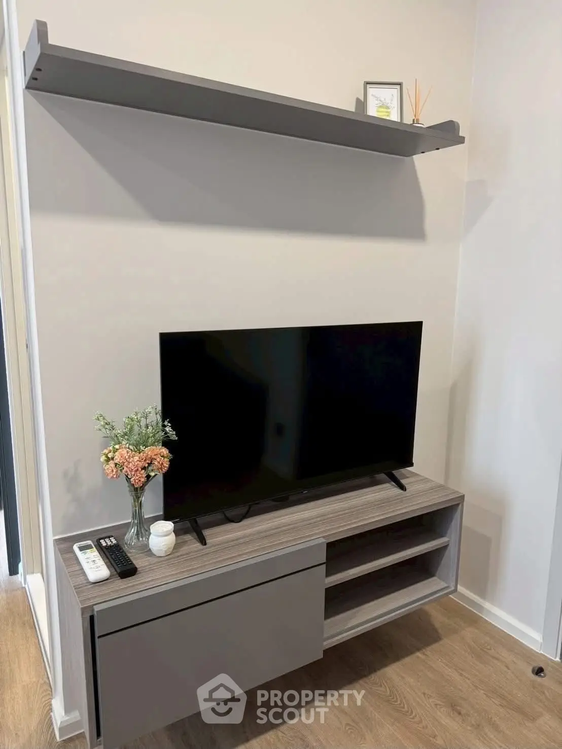 Modern living room with sleek TV stand and wall shelf, stylish decor.