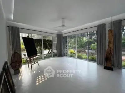 Spacious living room with large windows and garden view, perfect for natural light lovers.