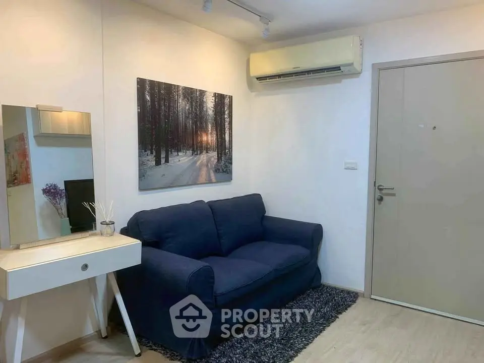Cozy living room with blue sofa, wall art, and air conditioning in modern apartment.