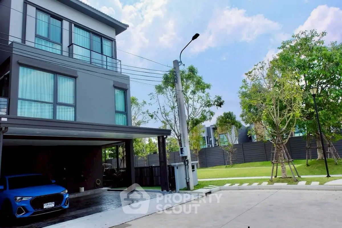 Modern three-story house with garage and landscaped garden in a serene neighborhood.