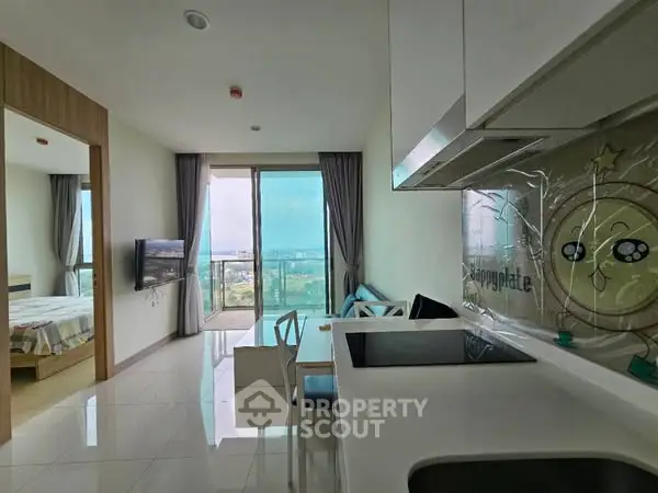 Modern open-layout apartment with kitchen and living area, featuring large windows and a scenic view.