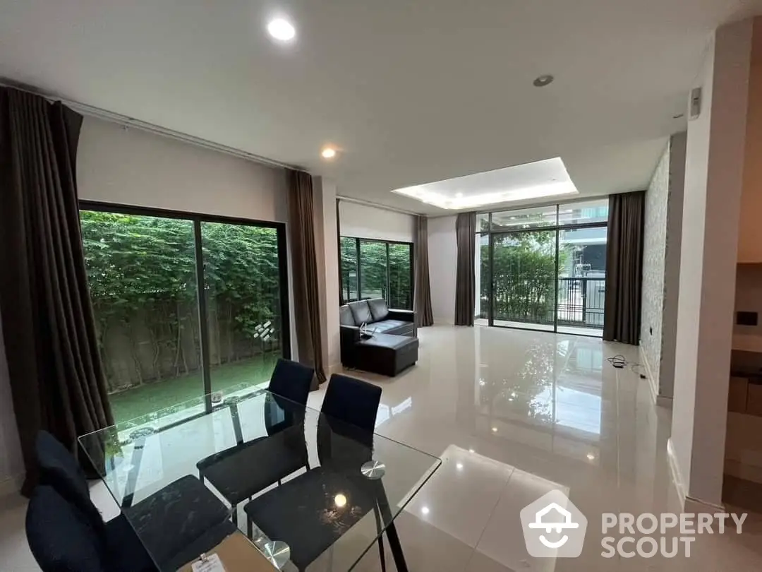 Spacious living room with polished floors, large windows, and direct access to a private garden, perfect for entertaining or relaxation.