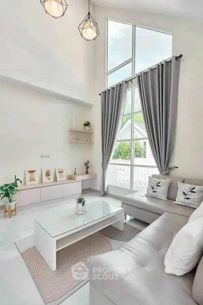 Modern living room with high ceilings, large windows, and elegant decor in a bright, airy space.