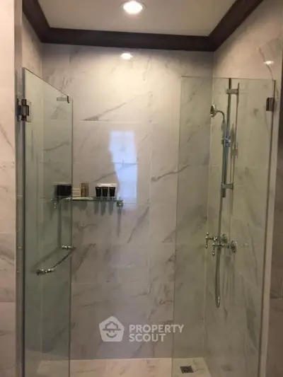 Elegant bathroom with glass shower enclosure and marble tiles