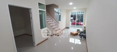Spacious modern living room with staircase and large windows for natural light.