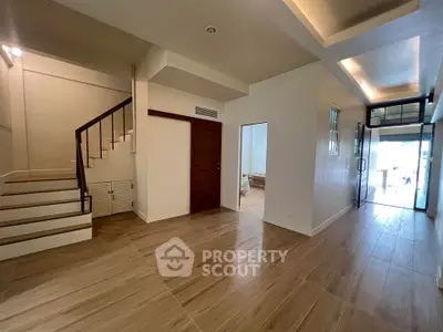 Spacious modern interior with wooden flooring and elegant staircase in a bright open layout.