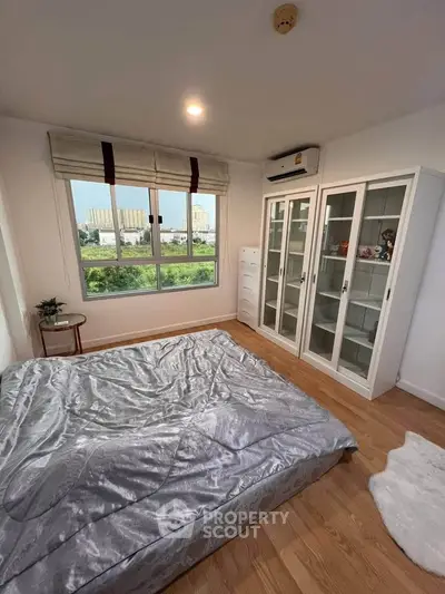 Bright bedroom with large window and modern furnishings, offering a serene view and ample storage space.