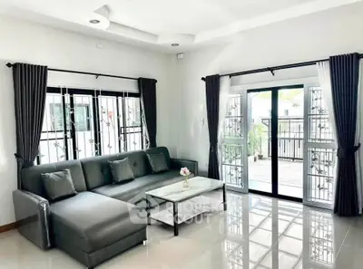 Spacious living room with modern sofa and large windows opening to a balcony, perfect for relaxation.