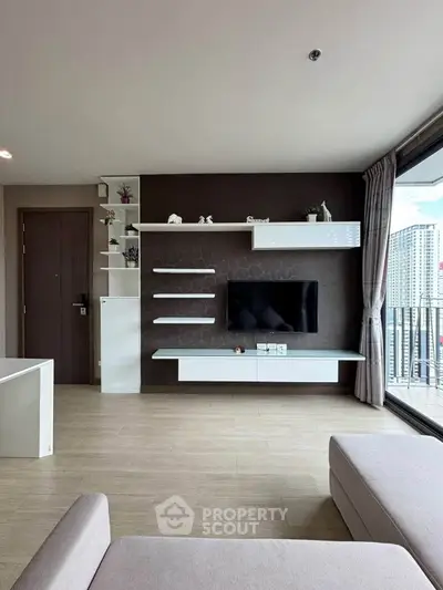 Modern living room with sleek TV unit and large balcony view in high-rise apartment.
