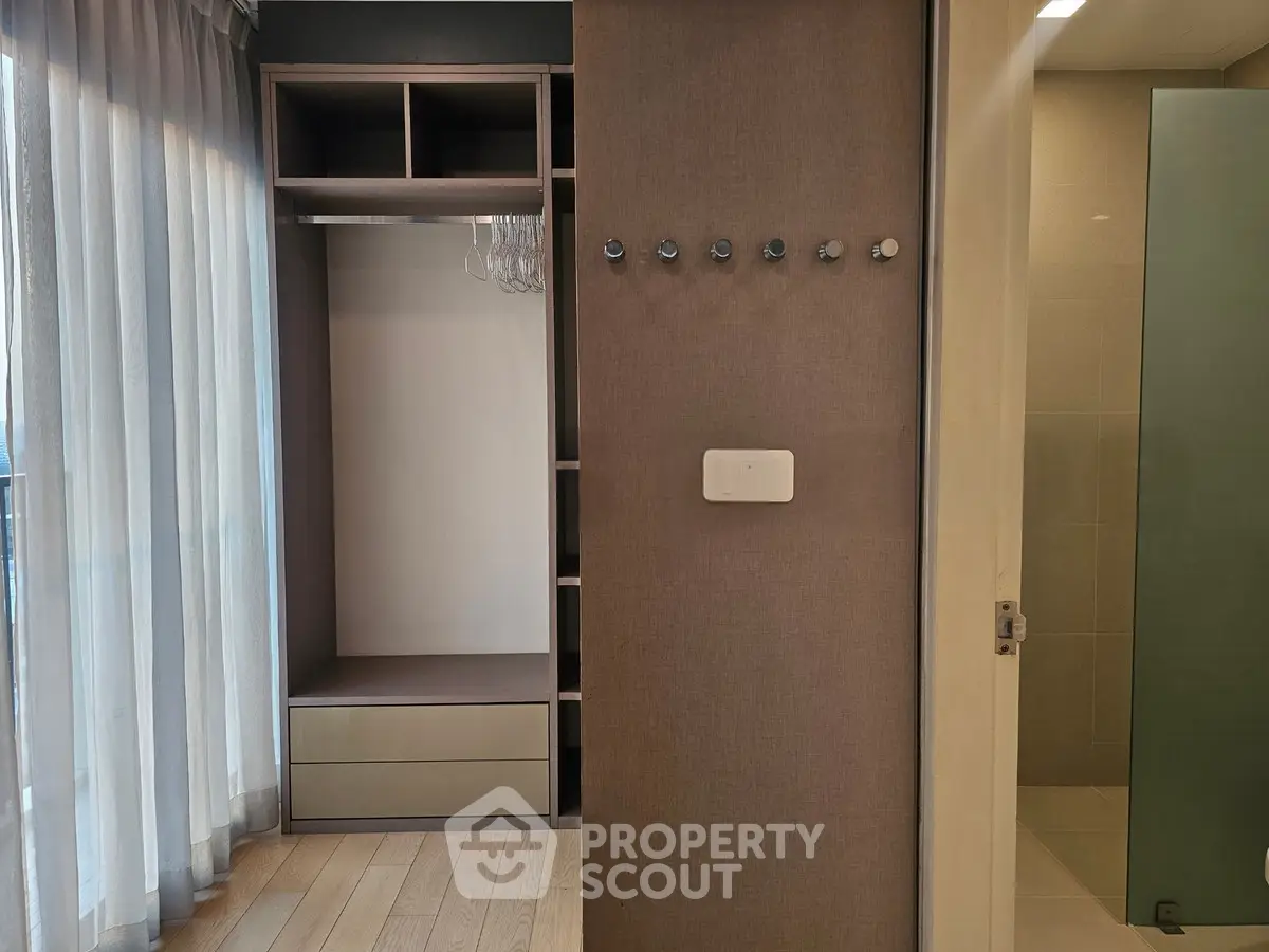 Modern interior with open closet and bathroom entrance, featuring sleek design and natural light.