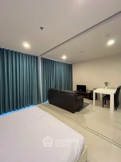 Modern studio apartment with cozy living area and dining space, featuring elegant curtains and sleek furniture.