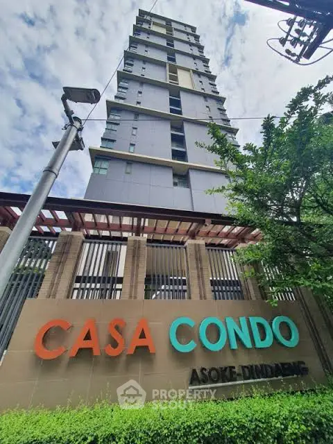 Modern high-rise condo building with lush greenery and clear sky view.