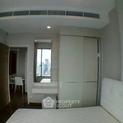 Modern bedroom with city view, featuring sleek wardrobe and minimalist design.