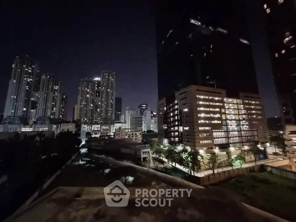 Stunning night view of modern city skyline with illuminated skyscrapers and lush greenery.