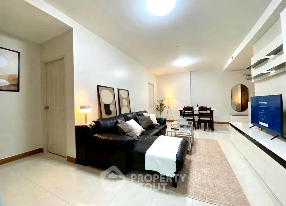 Spacious modern living room with sleek black sofa and elegant dining area