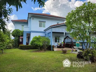 Charming blue two-story house with lush garden and covered patio