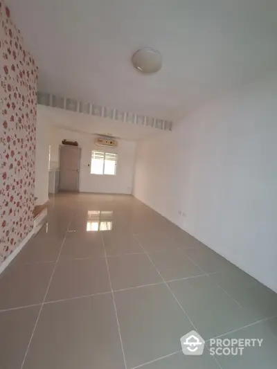 Spacious unfurnished room with tiled floor and floral accent wall