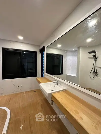 Spacious modern bathroom with large mirror and elegant wooden accents