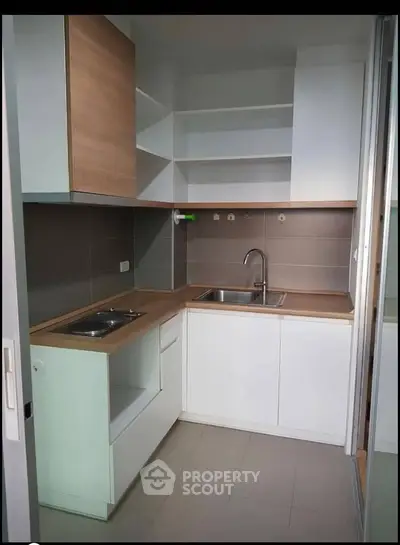 Modern compact kitchen with sleek cabinetry and integrated sink in a stylish apartment.