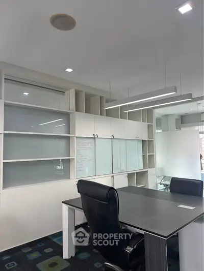 Modern office space with sleek desk and ergonomic chair, featuring built-in storage and contemporary lighting.