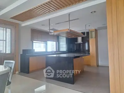 Modern kitchen with sleek black countertops and wooden cabinetry, featuring an open layout and ample natural light.