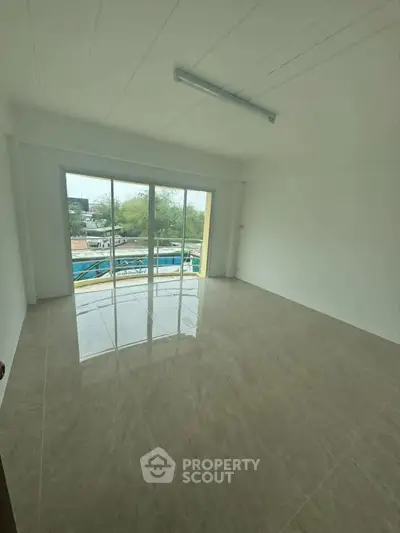 Spacious unfurnished room with large windows and balcony access, offering ample natural light and potential for customization.