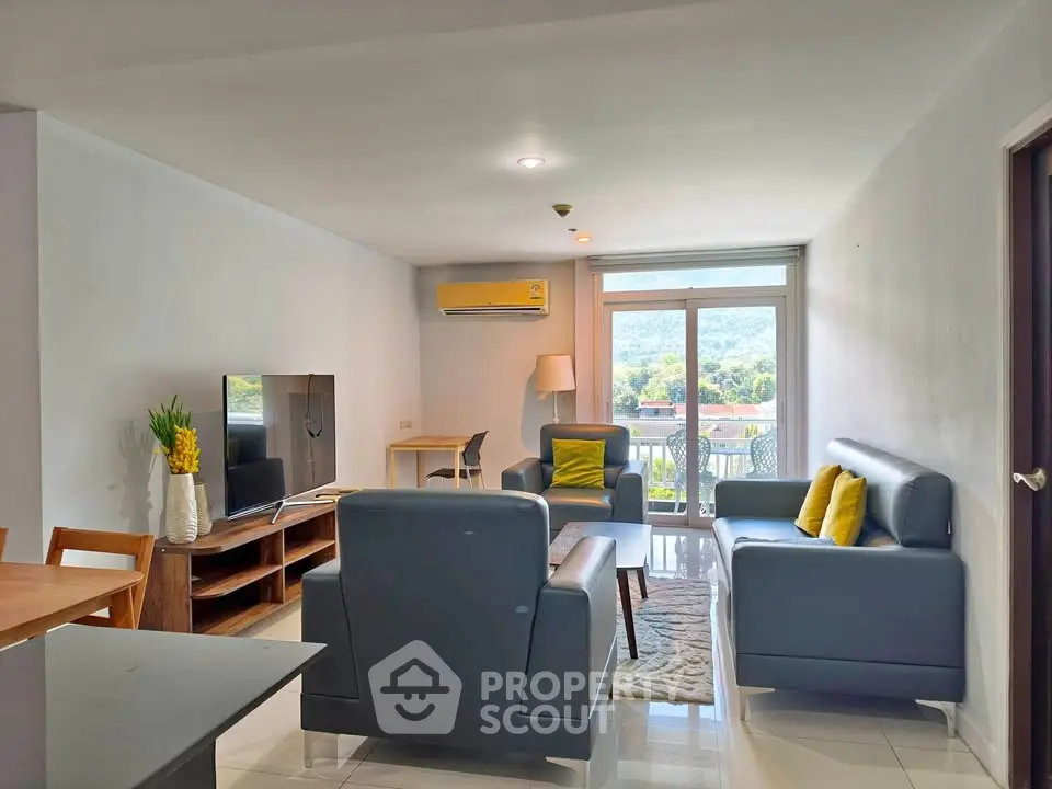 Spacious living room with modern furniture and scenic view from balcony.