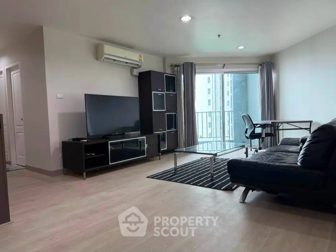 Spacious modern living room with sleek furniture and balcony view in urban apartment.