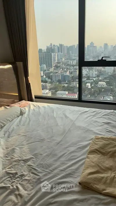 Luxurious bedroom with stunning city view from high-rise window, perfect for urban living.