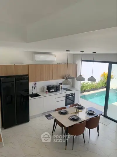 Modern kitchen with sleek design, pool view, and elegant dining area in luxury home.