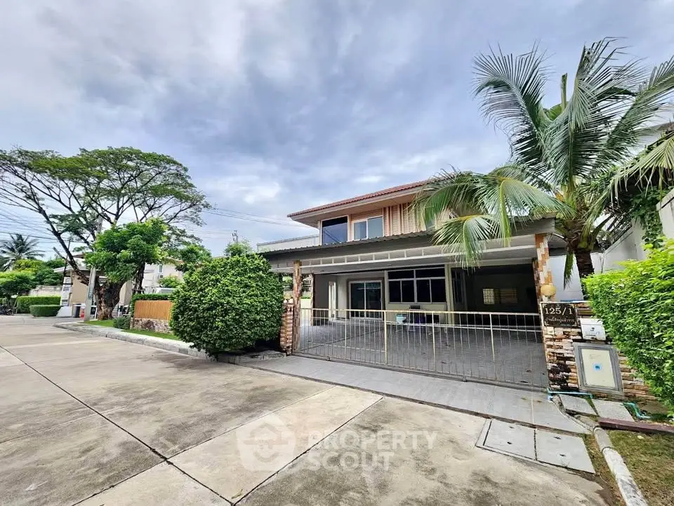 Spacious modern house with lush greenery and gated driveway in serene neighborhood.