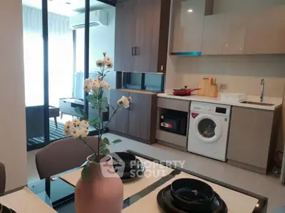Modern kitchen with washing machine and dining area in stylish apartment.