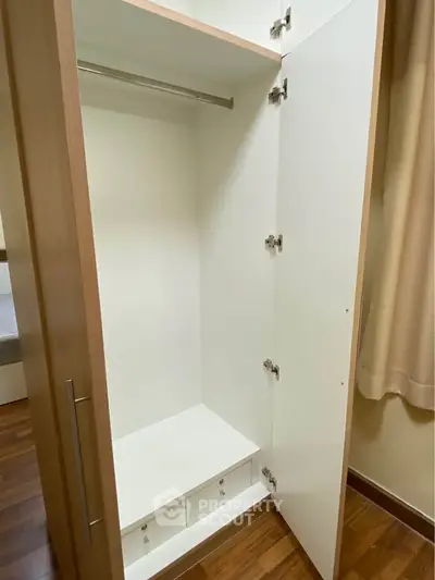 Spacious wooden wardrobe with open doors in a modern bedroom setting.