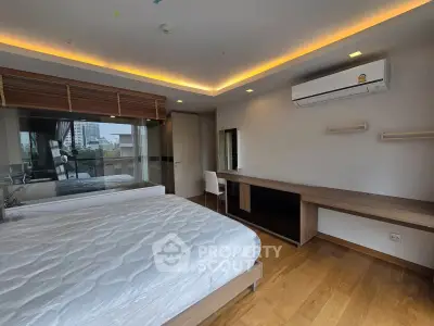 Modern bedroom with large window and city view, featuring a sleek air conditioner and stylish wooden flooring.